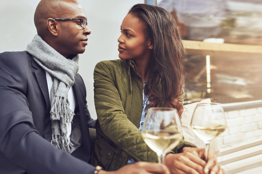 Male and female sitting, staring at each other while holding a glass of wine.