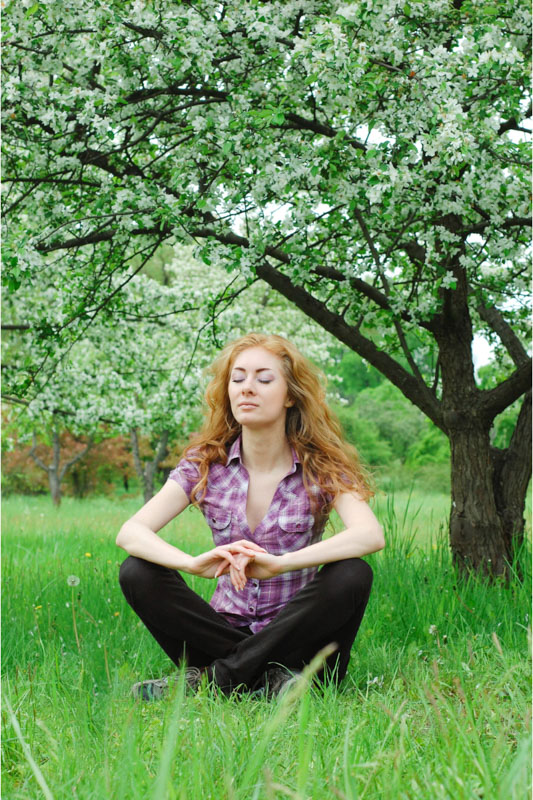 woman meditating under a tree