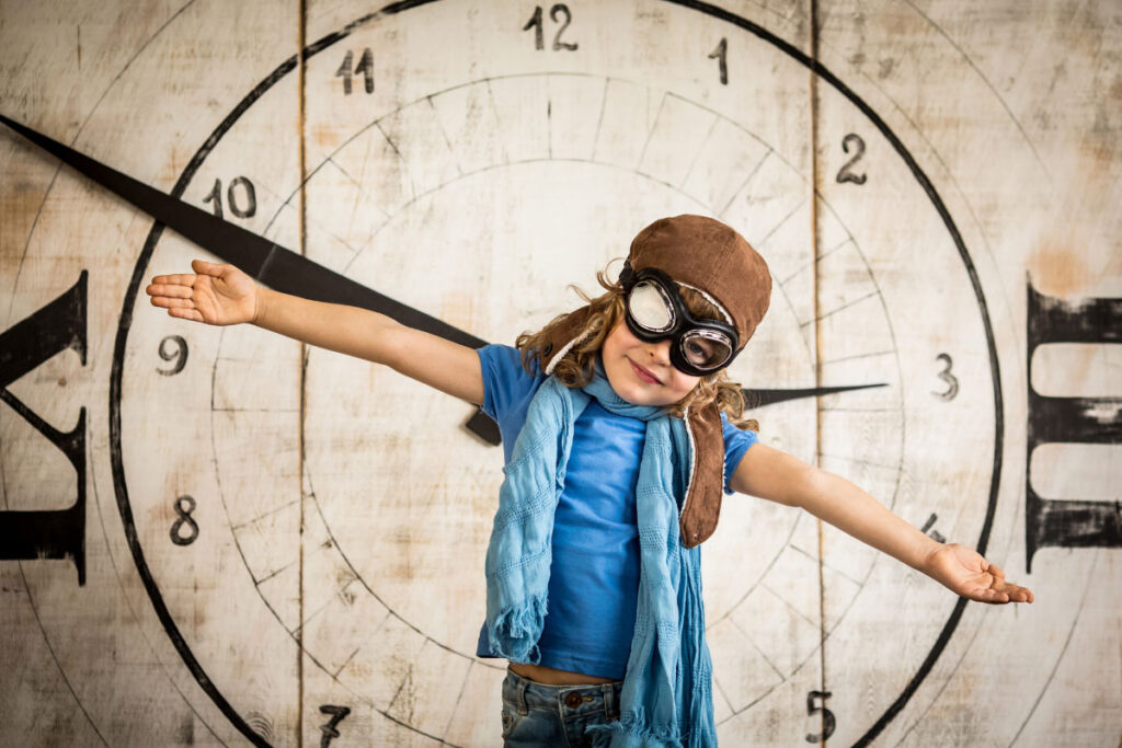 child pilot in front of clock