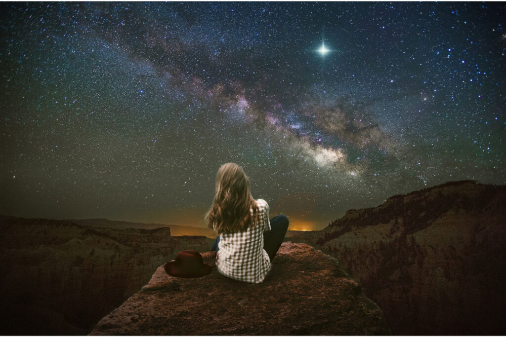 woman looking at stars in the sky from behind