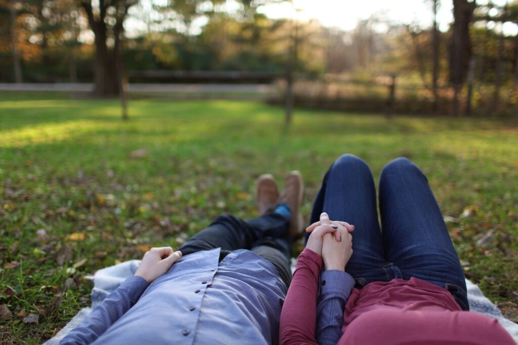 man and woman lying in park holding hands
