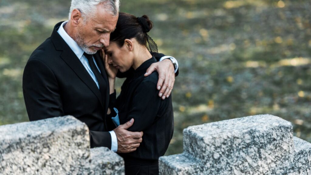 sad couple in black at a funeral cemetary