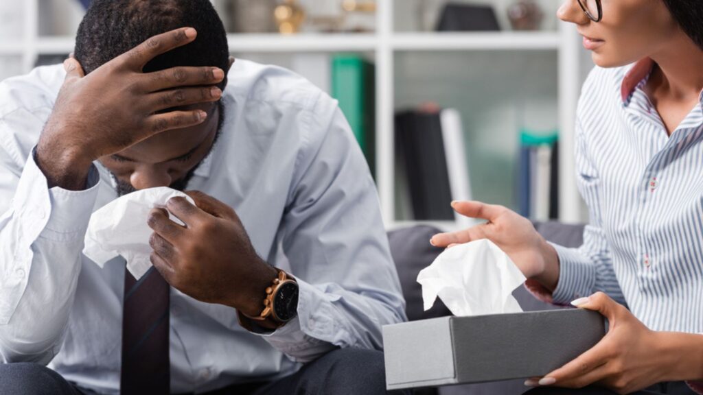 A Man with mental health issue and a Psychologist holding tissue paper for him
