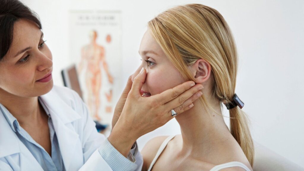 A doctor examining woman's nose