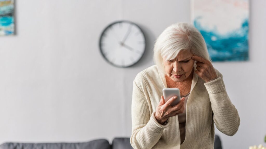 A thoughtful Senior woman wearing knit cardigan and top, Confused Old Woman Looking at the Phone, A clock Behind her