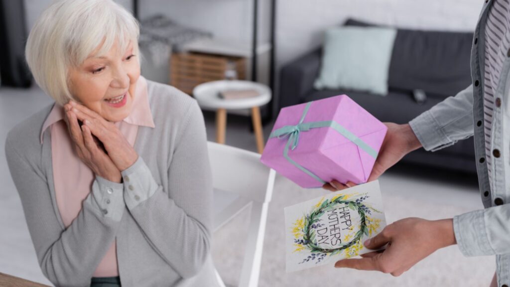 A woman giving a personalized Greeting card showing happy mother's day and a present to her mother, Mother is Happy