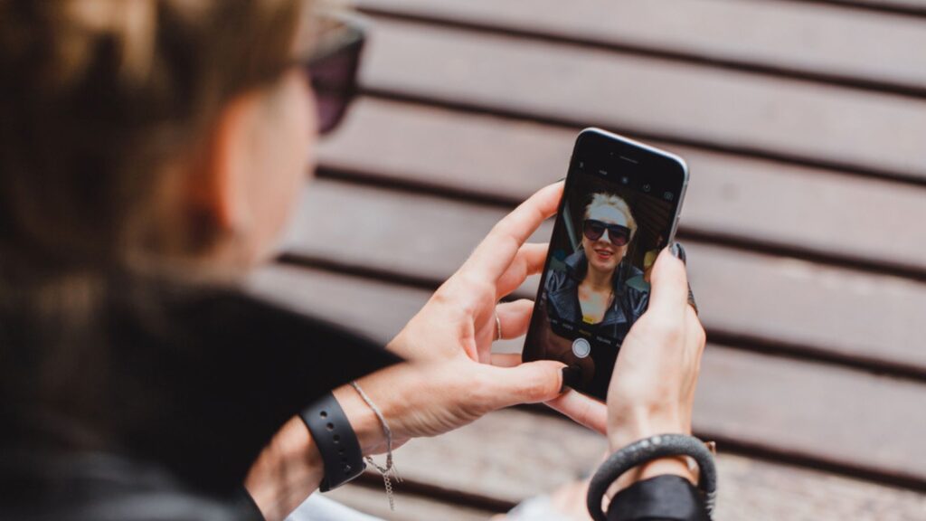 A woman taking selfie while sitting at the street bench