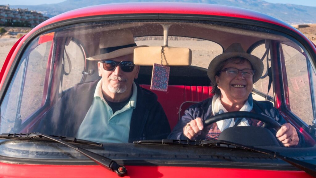 Drive an old red car for two seniors man and woman