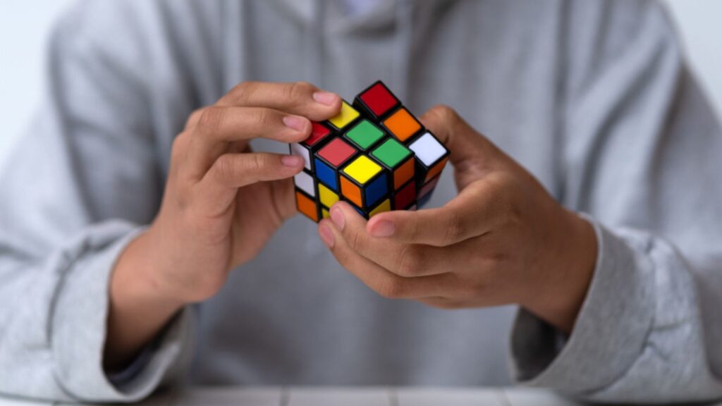 Man solving a Rubik's Cube. Illustrative editorial. Concept of problem solving, solution, focus and goal