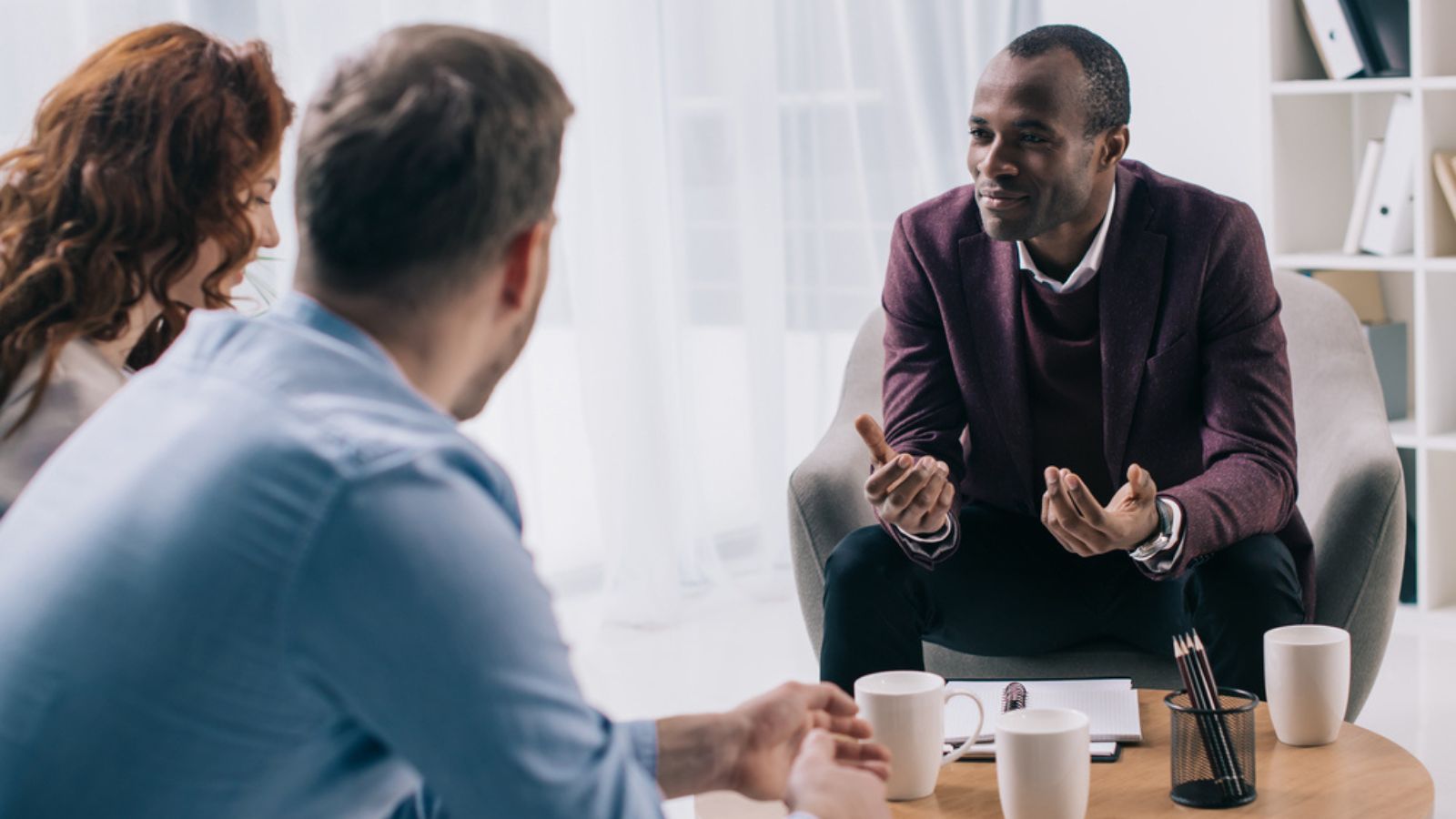 Smiling African American counselor talking to young couple in office
