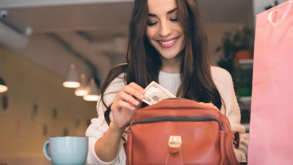 Smiling woman pulling out cash from bag