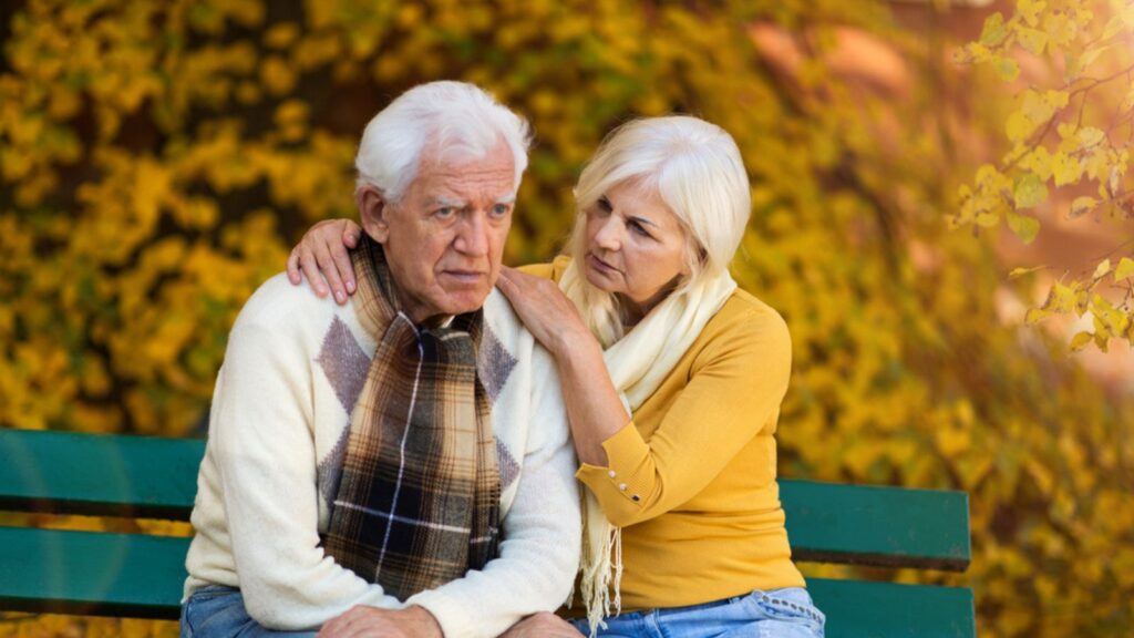 sad old couple at a park bench fall colors