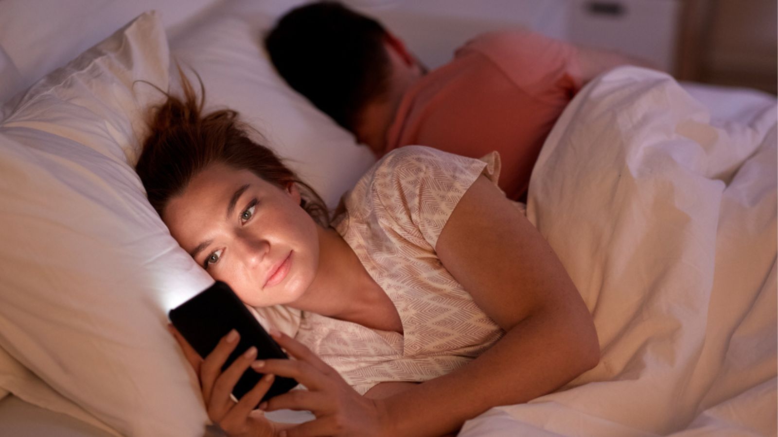Woman using smartphone while boyfriend is sleeping