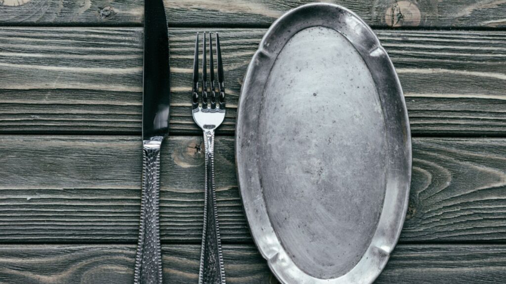 Knife and fork with silver tray on wooden table