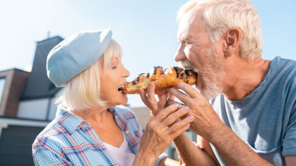 old couple happy eating a chocolate croissant