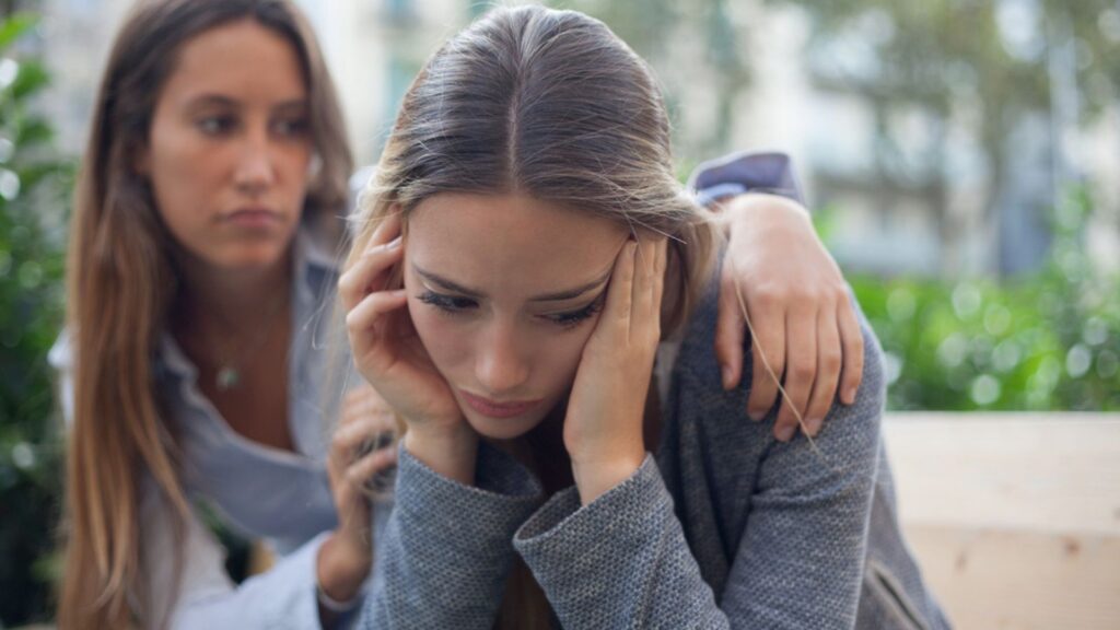 sad woman with her friend outside on a bench