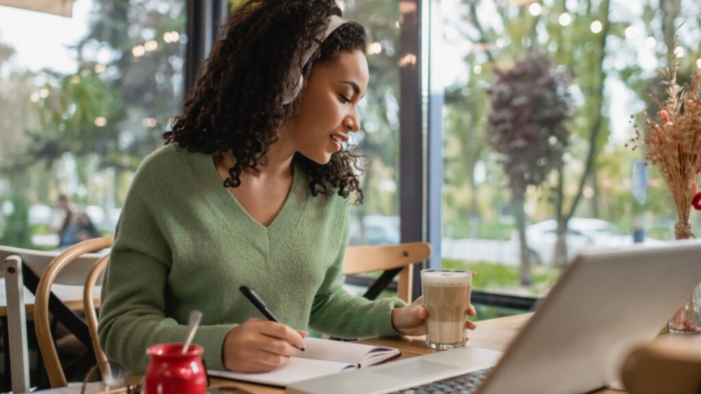 woman with headphones at a coffee shop with a laptop learning working
