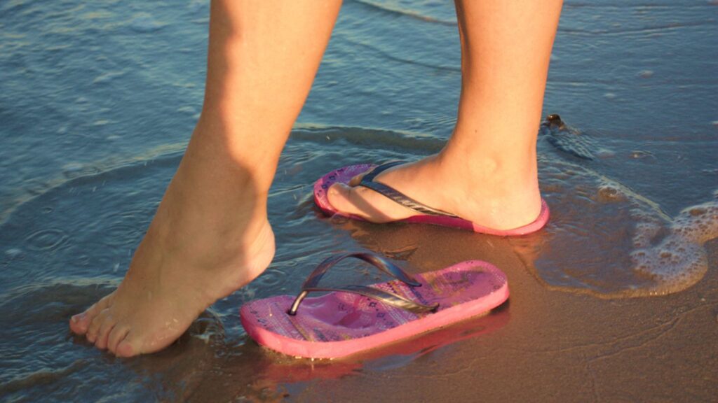 Woman's feet on the seashore at sunset