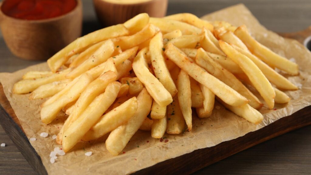 Delicious french fries on wooden table, closeup view