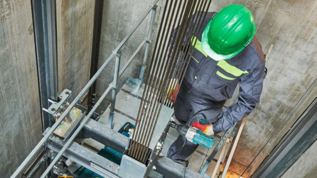 Lift machinist repairing elevator in lift shaft
