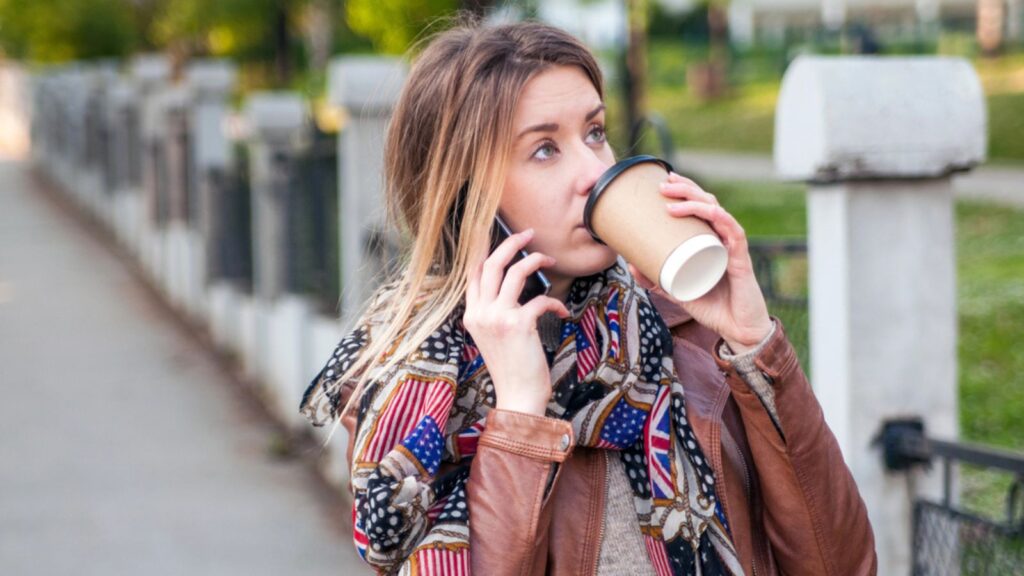 woman on the phone drinking coffee with an american scarf
