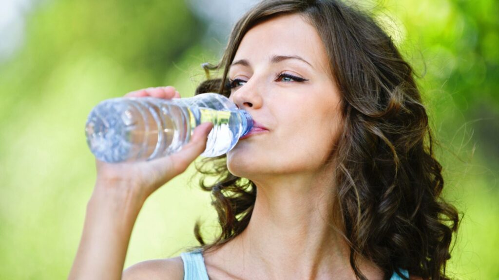 Young dark-haired woman drinking water