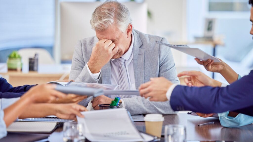 Businessman in meeting with headache, burnout or stress