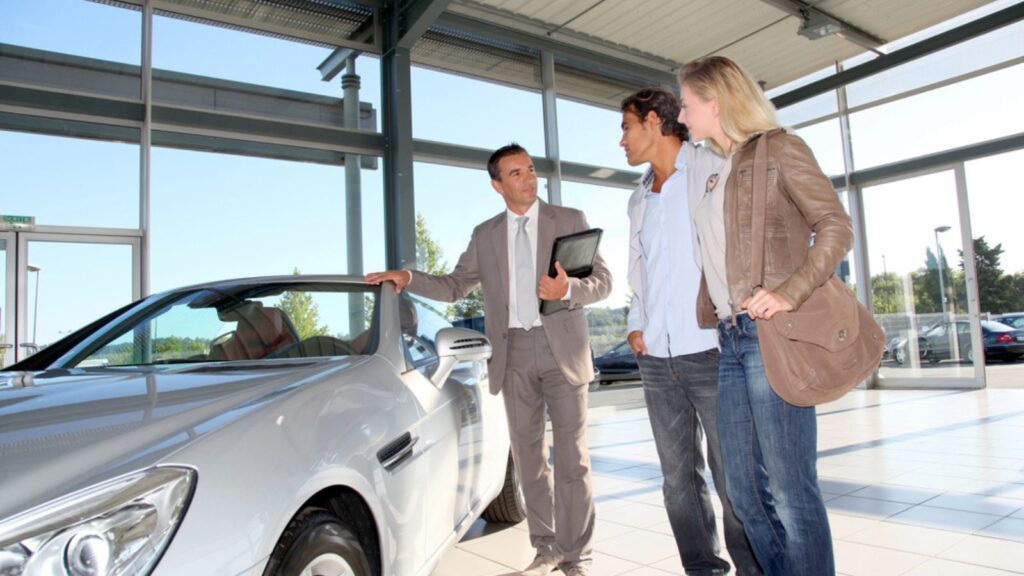 Car seller with couple in car dealership