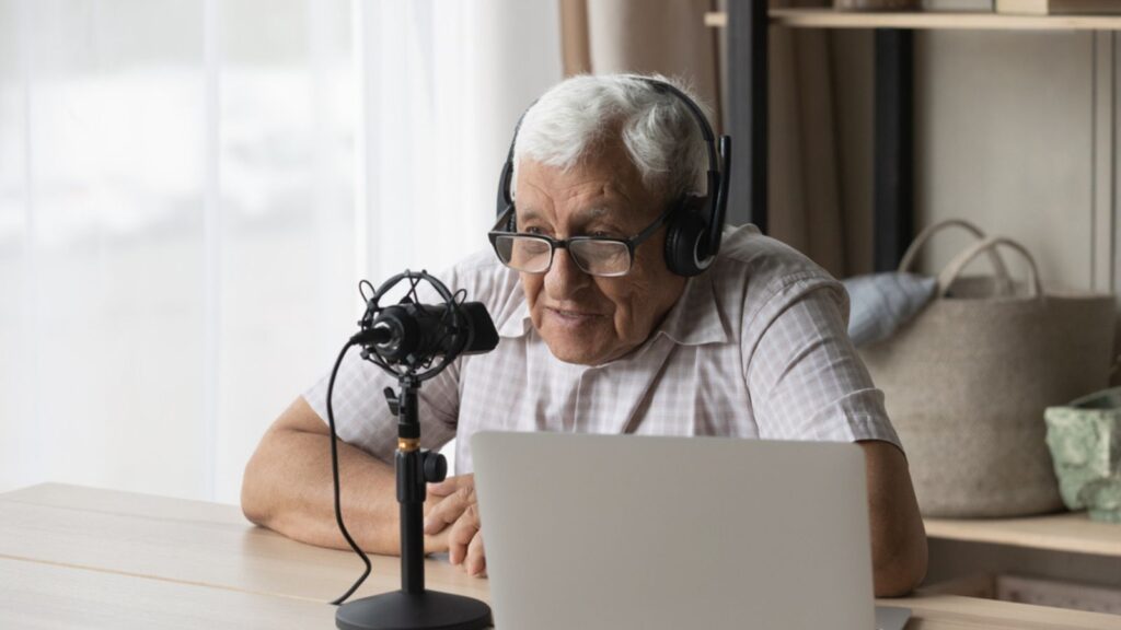 Elder radio host in headphones and glasses speaking at microphone as a Voiceover Artist