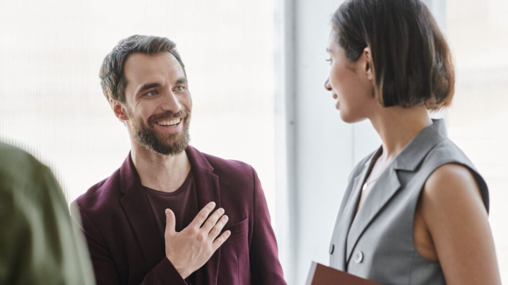 Grateful bearded entrepreneur man touching chest near young businesswoman