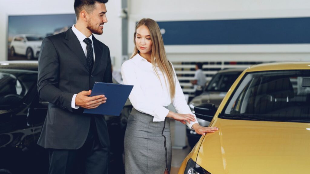Man car dealer showing a woman buyer a new car