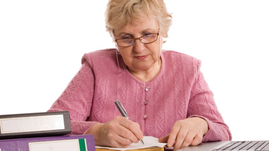 The elderly woman work as a Bookkeeper at the computer