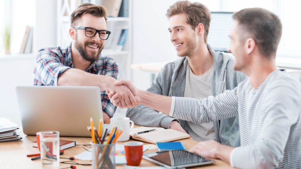 happy business men at a meeting shaking hands computer