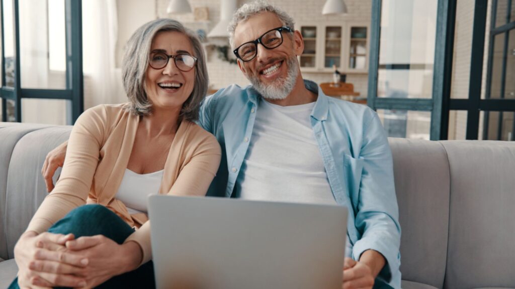 retired happy old couple on the couch with their computer