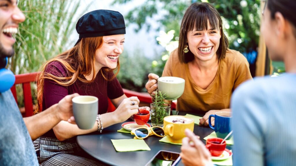 laughing friends drinking coffee at a table happy