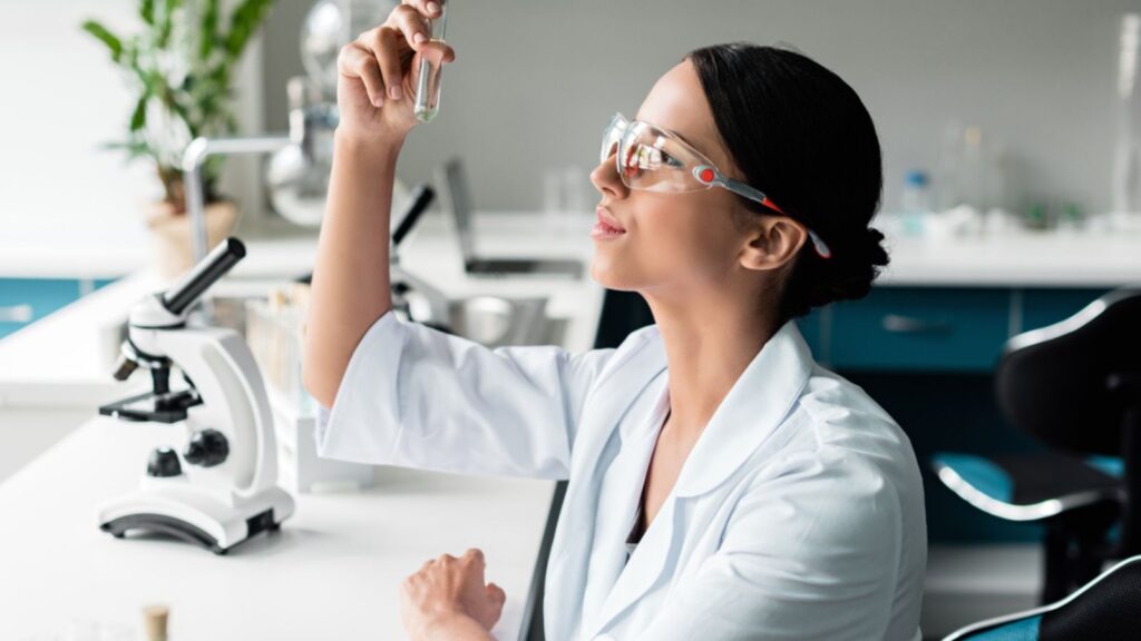 scientist chemist working looking at a specimen microscope