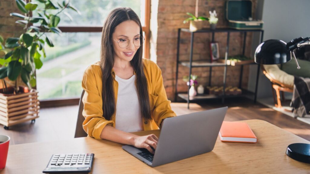woman at her happy computer working in a home office with plants laptop