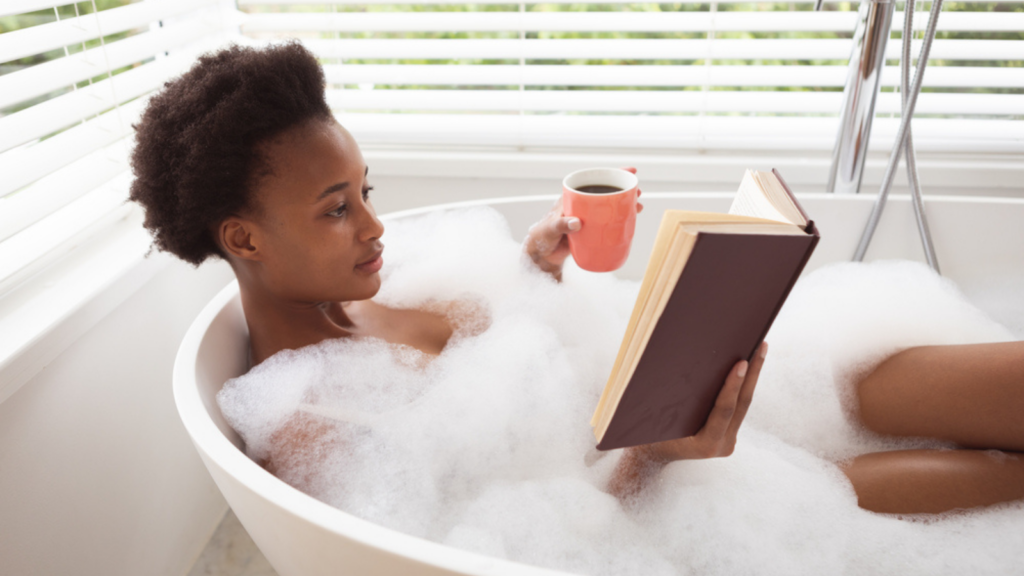 woman in the bath with coffee and book self care