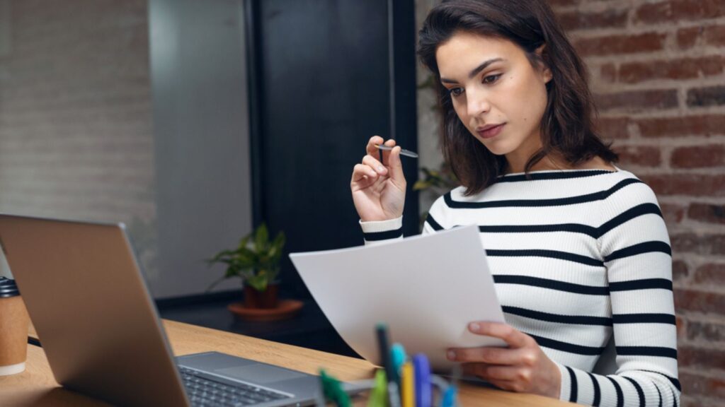 Woman working with laptop while studying the documents