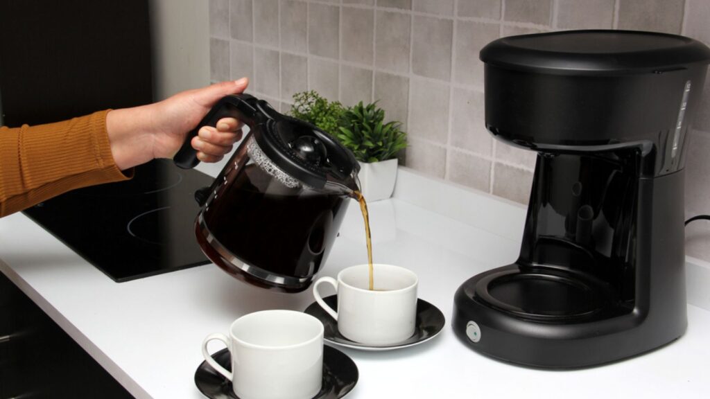 Woman's hands serve coffee prepared in a coffee maker to start the day