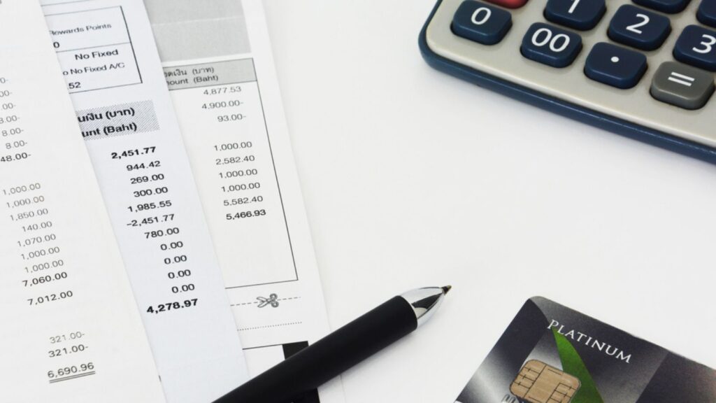 Close up of a credit cards with credit card statements, pen and calculator on white background, copy space