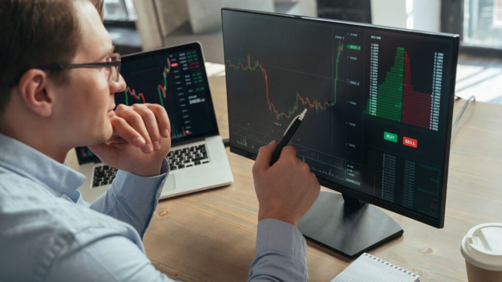 Concentrated businessman trader looking at laptop pc monitor with diagram of stock crypto currency market