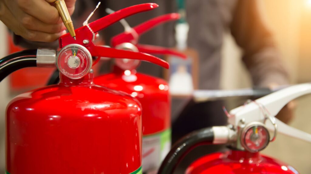 Fire fighter are checking pressure gauge of red fire extinguishers tank in the building