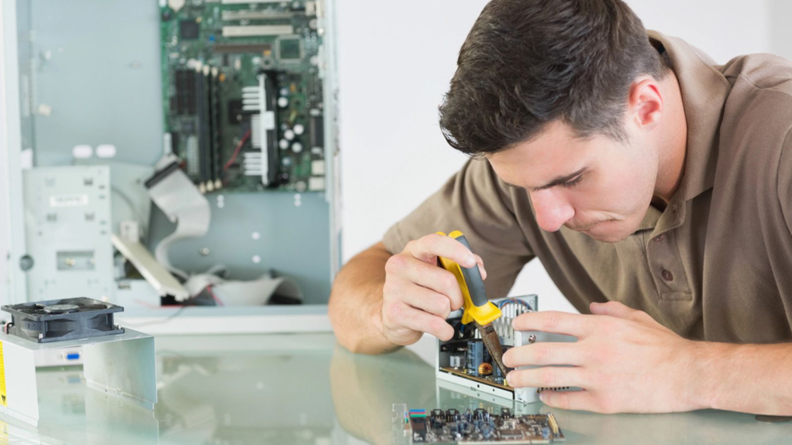Handsome serious computer engineer repairing hardware with pliers .