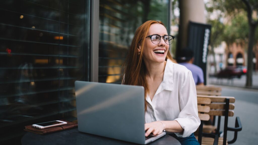 Happy woman in glasses sitting with laptop working remote professional
