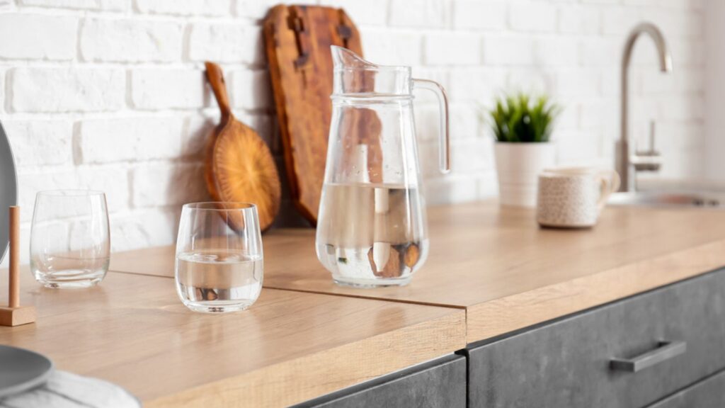 Jug and glass of water on table top in kitchen
