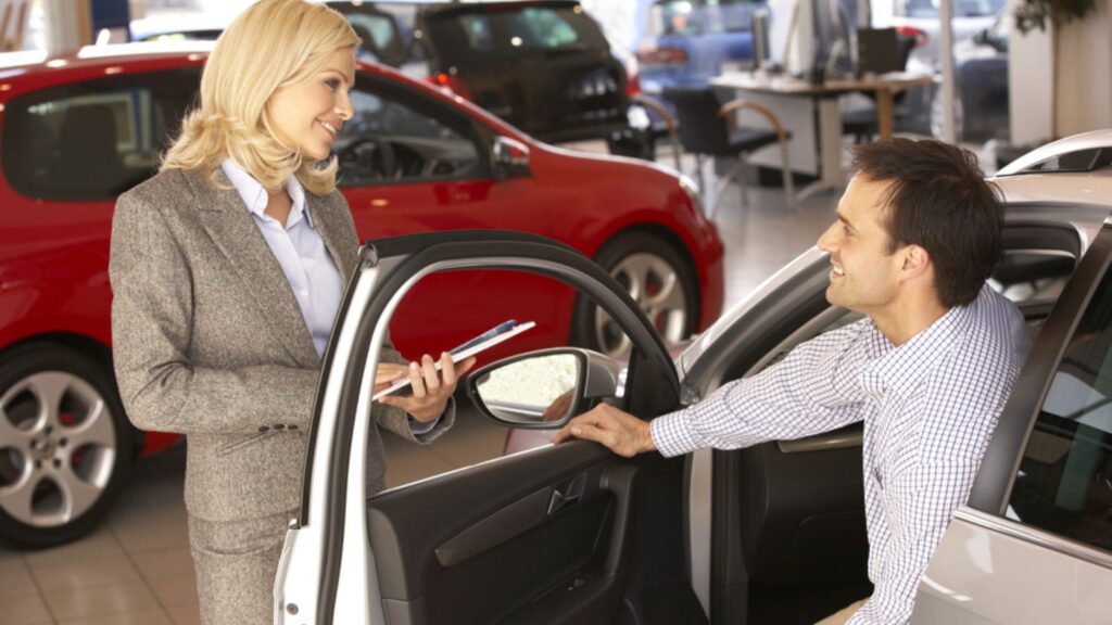 Man buying a car and talking to car saleswoman