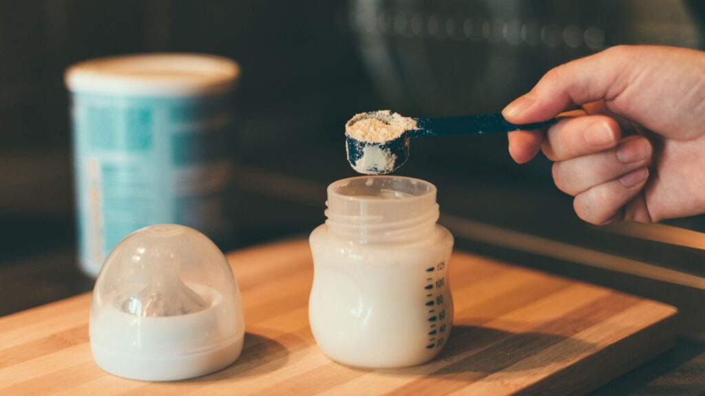 Mother making baby formula in milk bottle milk powder.