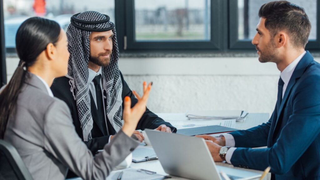 Multicultural business partners man and woman with laptop and documents on meeting with translator in office