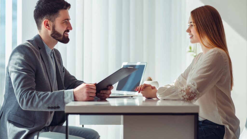 Nervous woman looking at manager reading her resume during a job interview at office. Side view